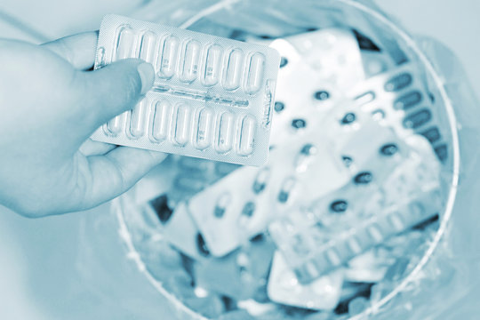 Medikament wird in den M&uuml;ll entsorgt ,Focus Hand mit Tabletten in leicht blau . 