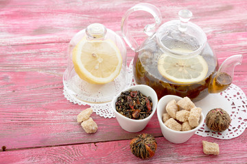 Ripe lemon, cinnamon and fruit drink in glass teapot on wooden