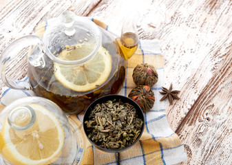 Ripe lemon, cinnamon and fruit drink in glass teapot on wooden