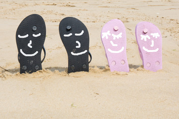 Pink and black  beach flip flops with  in white sand on sea background