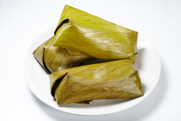 Traditional Thai dessert, Glutinous rice streamed with banana wrap banana leaf. (Khao Tom Mat) isolated on white background