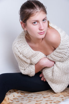 Cute blonde wearing knitted woolen pullover. House wall as background