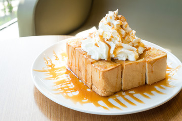 Golden honey toast in the white dish with whipped cream on top