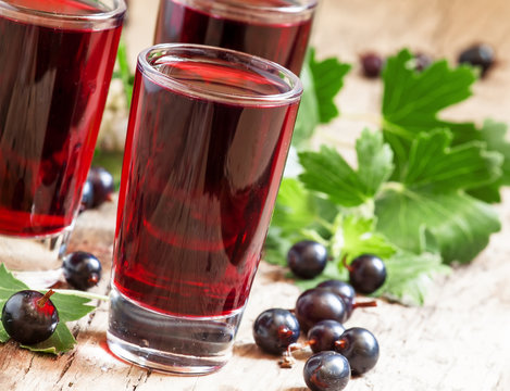 Fresh black currant juice with berries in glasses on an old wood