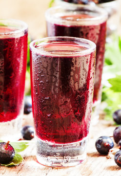 Fresh black currant juice with berries in glasses on an old wood