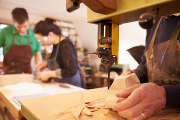 Hands of shoemaker shaping shoe lasts in a workshop