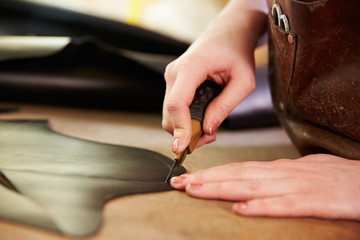 Obraz na płótnie Canvas Shoemaker cutting leather in a workshop, close up