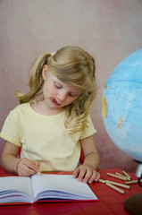 concentrated little girl, notepad and globe