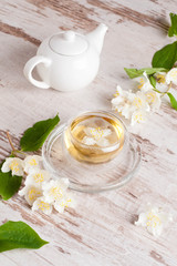 Fototapeta na wymiar Glass cup of green tea with jasmine on wooden background