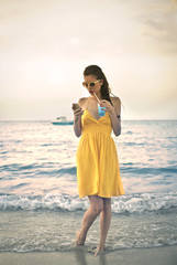 Girl dressed in yellow sending text messages by the sea