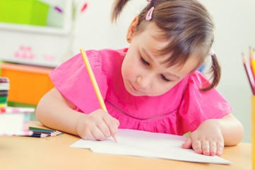 Cute little girl drawing with colorful pencils