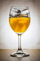 Orange juice with ice in wine glass, warm tone