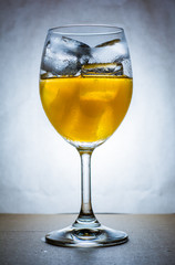 Orange juice with ice in wine glass, cool tone