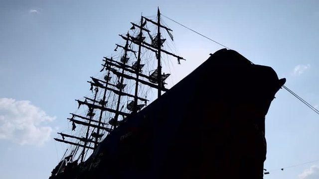 The silhouette of a large wooden ship with mast and sail against