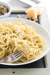 plate of spaghetti with pesto and cheese, vertical