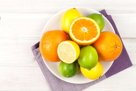 Citrus fruits on plate. Oranges, limes and lemons