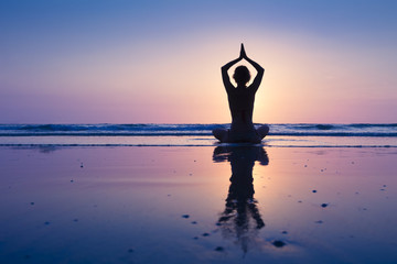 Young healthy woman practicing yoga on the beach