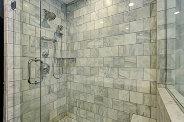 Luxury bathroom with white and grey marble and glass shower.