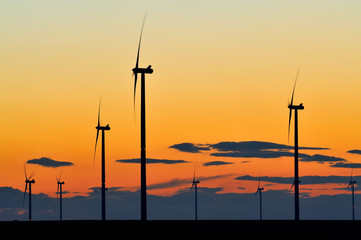 Obraz premium Wind turbine farm with rays of light at sunset