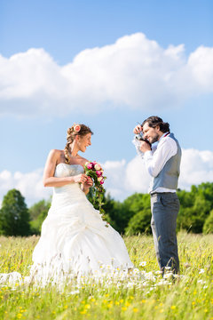Wedding couple taking pictures on meadow