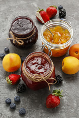 Strawberry, blueberry and peach jams in glass jars