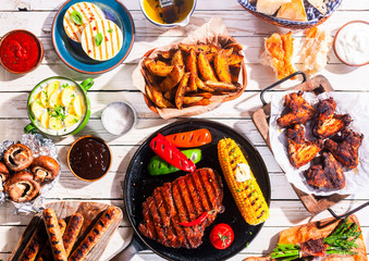 Barbequed Meats and Vegetables on Picnic Table © exclusive-design