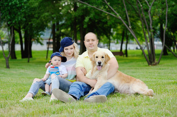 Obraz premium family with a dog retriever on the grass
