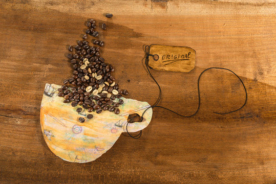 Tazza di caffè in carta colorata e chicchi di caffè su un piano di legno grezzo.