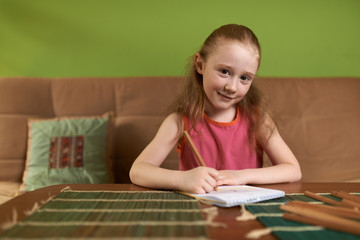 Cheerful girl in pink dress drawing pencils