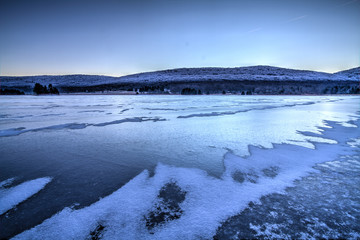 Frozen blue lake in middle of winter with snow