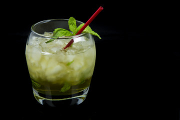 A Mint Julep, the official drink of the Kentucky Derby, with fresh mint leaves, crushed ice, and a red stir stick with a black background. Drink is oriented on the left side of the photo. - obrazy, fototapety, plakaty