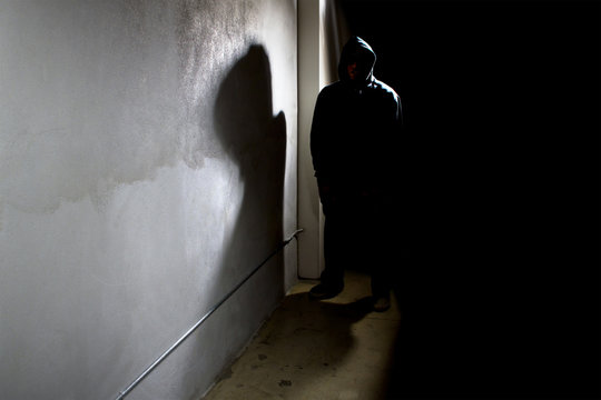 Hooded Criminal Stalking In The Shadows Of A Dark Street Alley