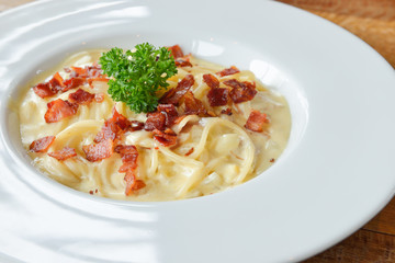 Spaghetti carbonara with ham, cheese and parsley