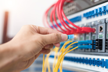 Man connecting fiber network cables to switches