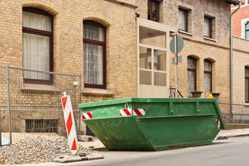 Fototapeta na wymiar Ein grüner Container steht am Strassenrand vor einem Haus