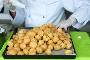 Pasticcere all'opera: riempire i bignè al fine di assemblare una torta.