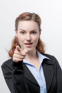 Junge Frau im Blazer zeigt mit dem Finger