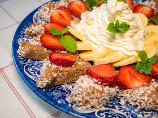 Chocolate dessert with banana and strawberry under whipped cream