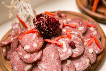 Salame italiano a fette su piatto di legno