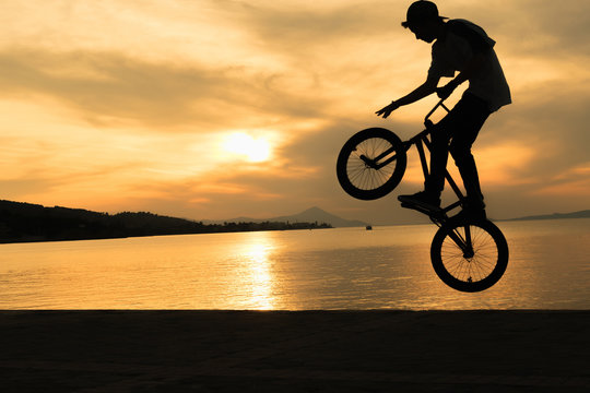 Bmx biker tricks against a beautiful sunset.
