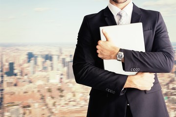 Composite image of mid section of businessman holding computer 