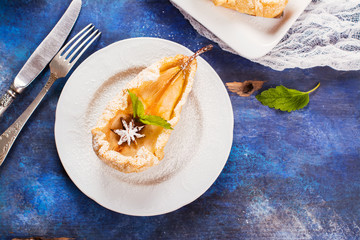 Delicious hot dessert: baked pears in pastry on rustic wooden background. Selective focus