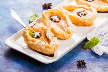 Delicious hot dessert: baked pears in pastry on rustic wooden background. Selective focus