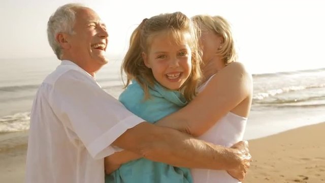 grandparents and granddaughter on beach
