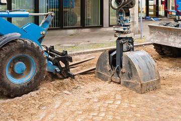 Die Doppelschaufel von einem Bagger und ein Radlader mit Gabel