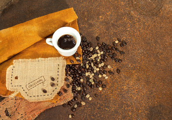 Caffè nero con tazzina cucita in juta e chicchi di caffè su texture di ruggine.
