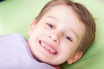 Smiling child with happy face on dentist chair or office