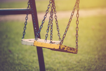 Empty chain swing in children playground. Retro filter.