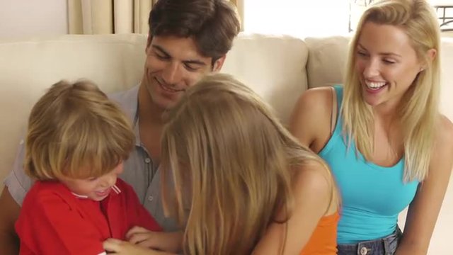Brother and sister tickling each other on sofa.