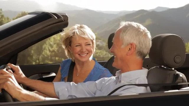 senior couple driving convertible car